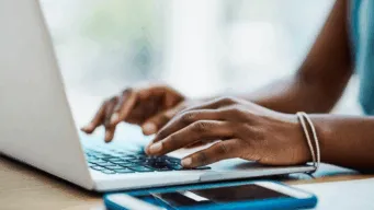 two hands typing on a laptop