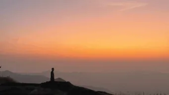 silhouette of man on top of cliff with sunset thinking about AI-augmented devops and how generative AI in software development is opening devops to a wide unknown.