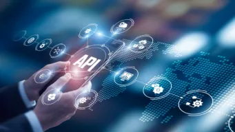 business man's hands holding a tablet with "API" on it; automated functional testing icons hover around it, indicating API testing in the age of everything-as-code.