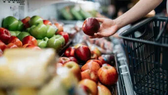 Shopper picking out apples at grocery store