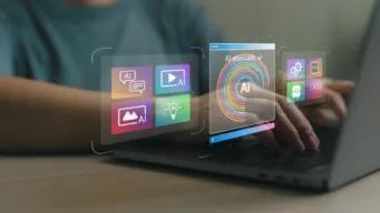 Hands typing at laptop with holograms in foreground reflecting "AI assistant"