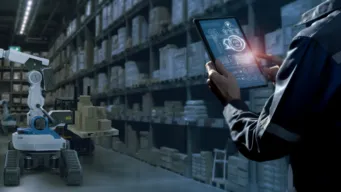 worker uses tablet to direct robot as it moves packages in a warehouse, indicating identity as the new perimeter.