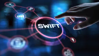dark background with round button that reads SWIFT; worker is pointing to it about to start ISO 20022 bank modernization