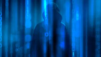 An image of a hacker behind a curtain representing the hidden risk of ransomware.