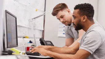 two men in an office collaborating, using devops for manufacturing