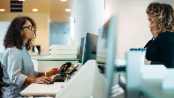 Smiling administrator talking to woman standing at reception
