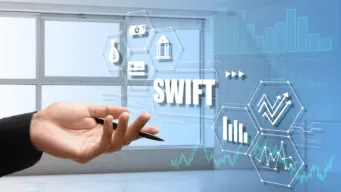 bright background with workers hand indicating toward SWIFT and banking icons on a transparent screen, showing SWIFT infrastructure TCO