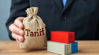 a hand holding a small brown bag that reads "tariffs"