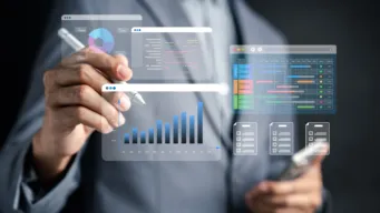 black background with mid-shot of male worker standing, about to write on the transparent board set between him and the viewer; the board displays ERP graphs and other modern enterprise planning charts