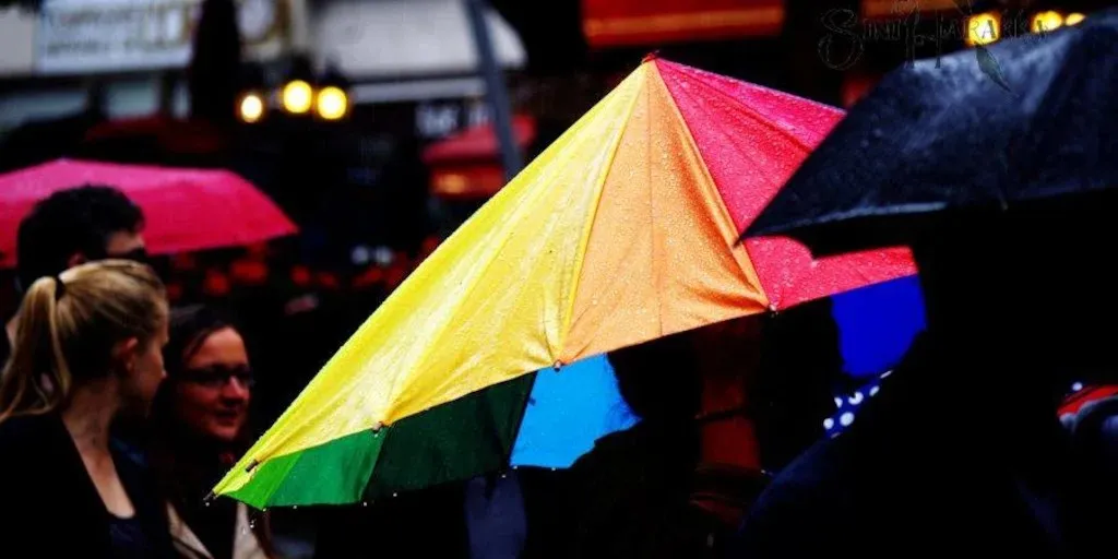 A large rainbow umbrella dominates two-thirds of the picture.